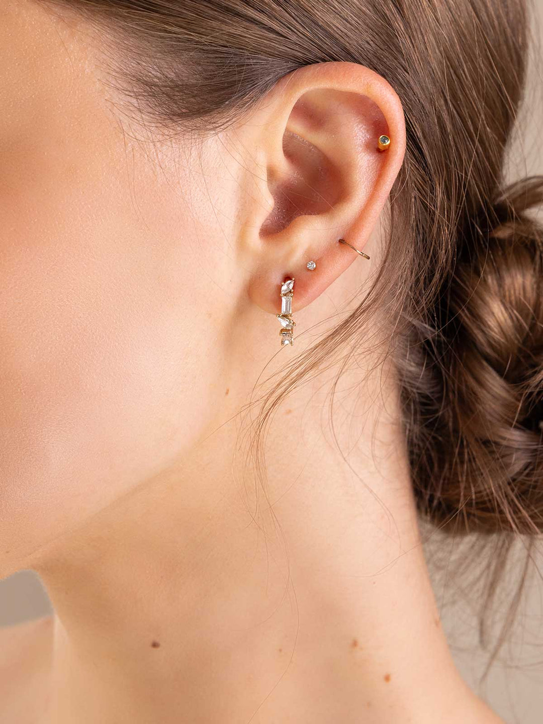 Close-up of an ear with gold hoop earrings